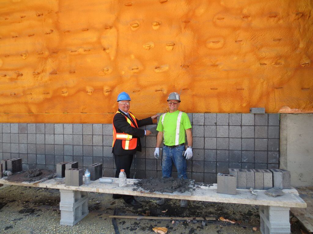 Terry Sheehan, le député fédéral de Sault Ste. Marie pose une brique sur le nouveau bâtiment des opérations.